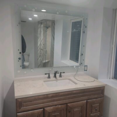 A Custom Glass Unlimited Bathroom Mirror with decorative framing.