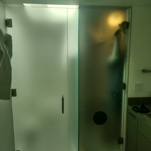 Frameless shower door and enclosure with frosted glass.